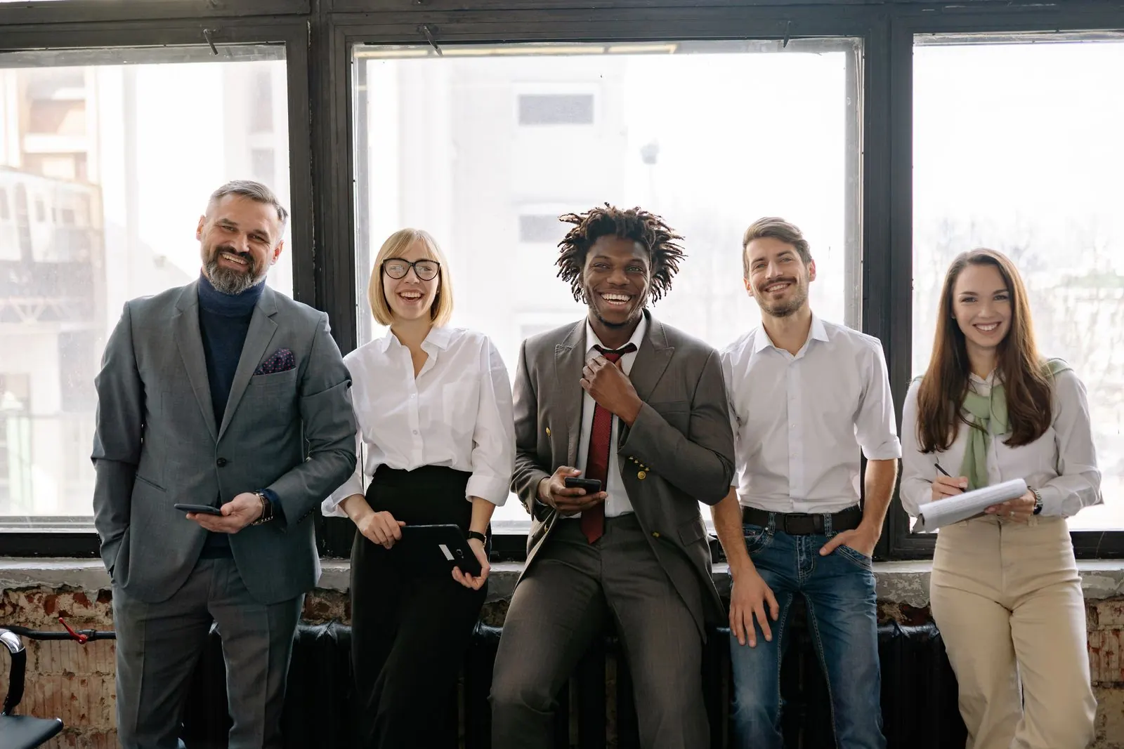 A group of colleagues standing together by office windows