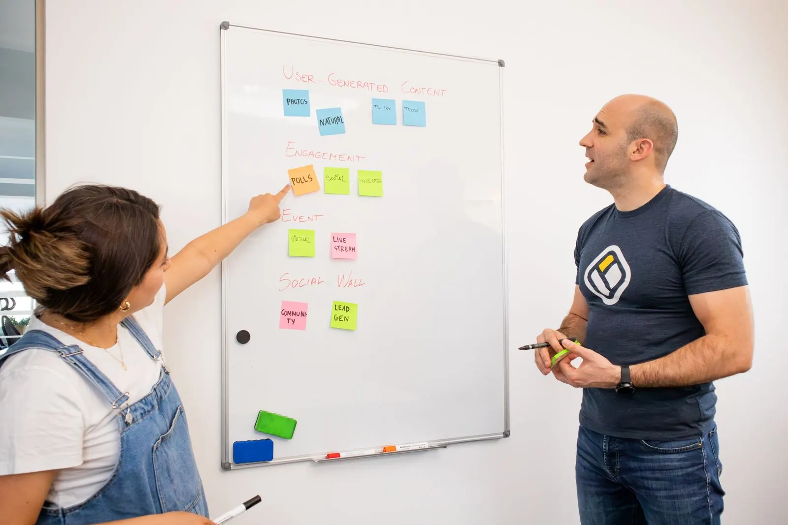 Two colleagues planning with sticky notes on a whiteboard