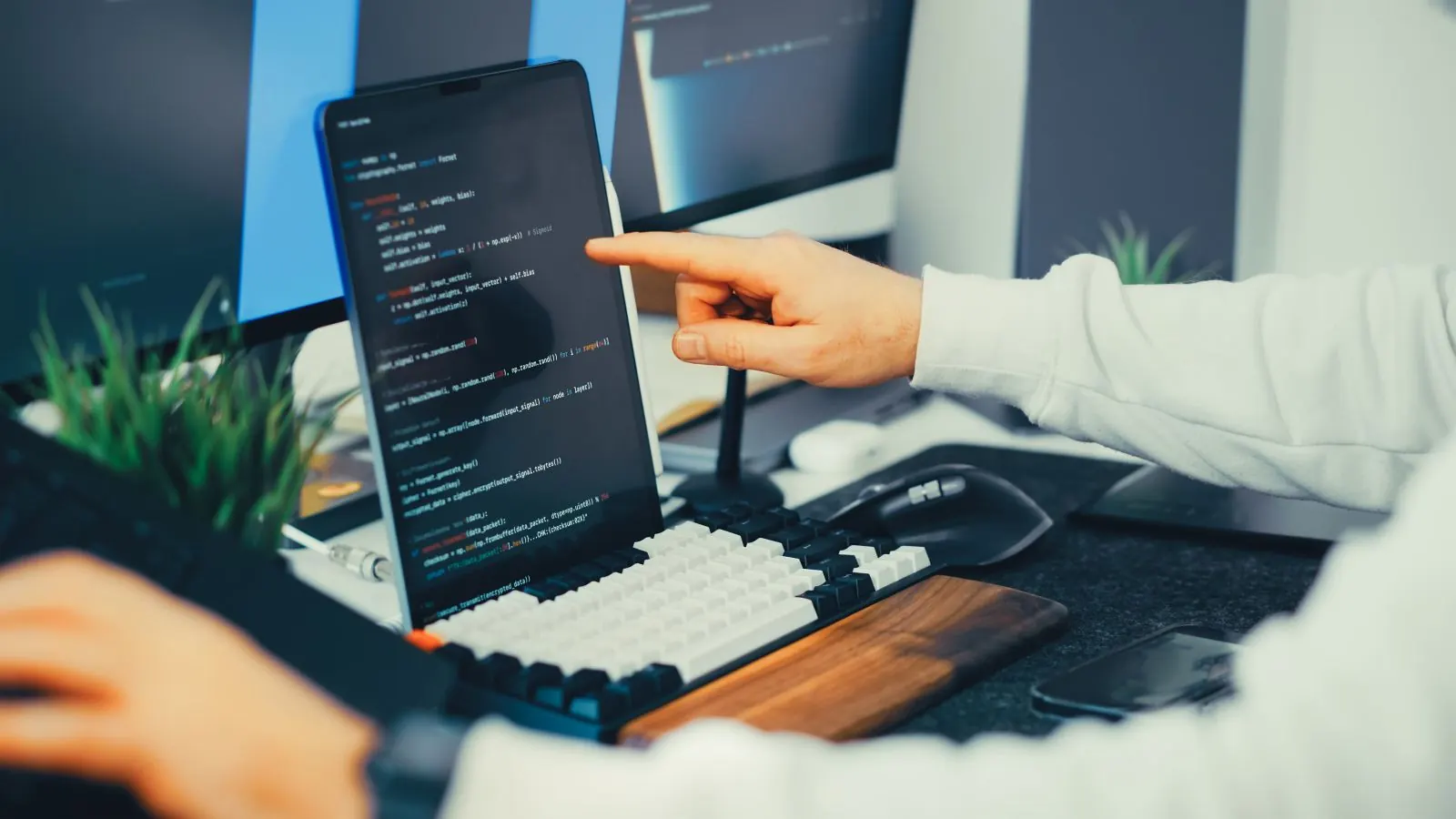 A hand pointing at code on a laptop screen