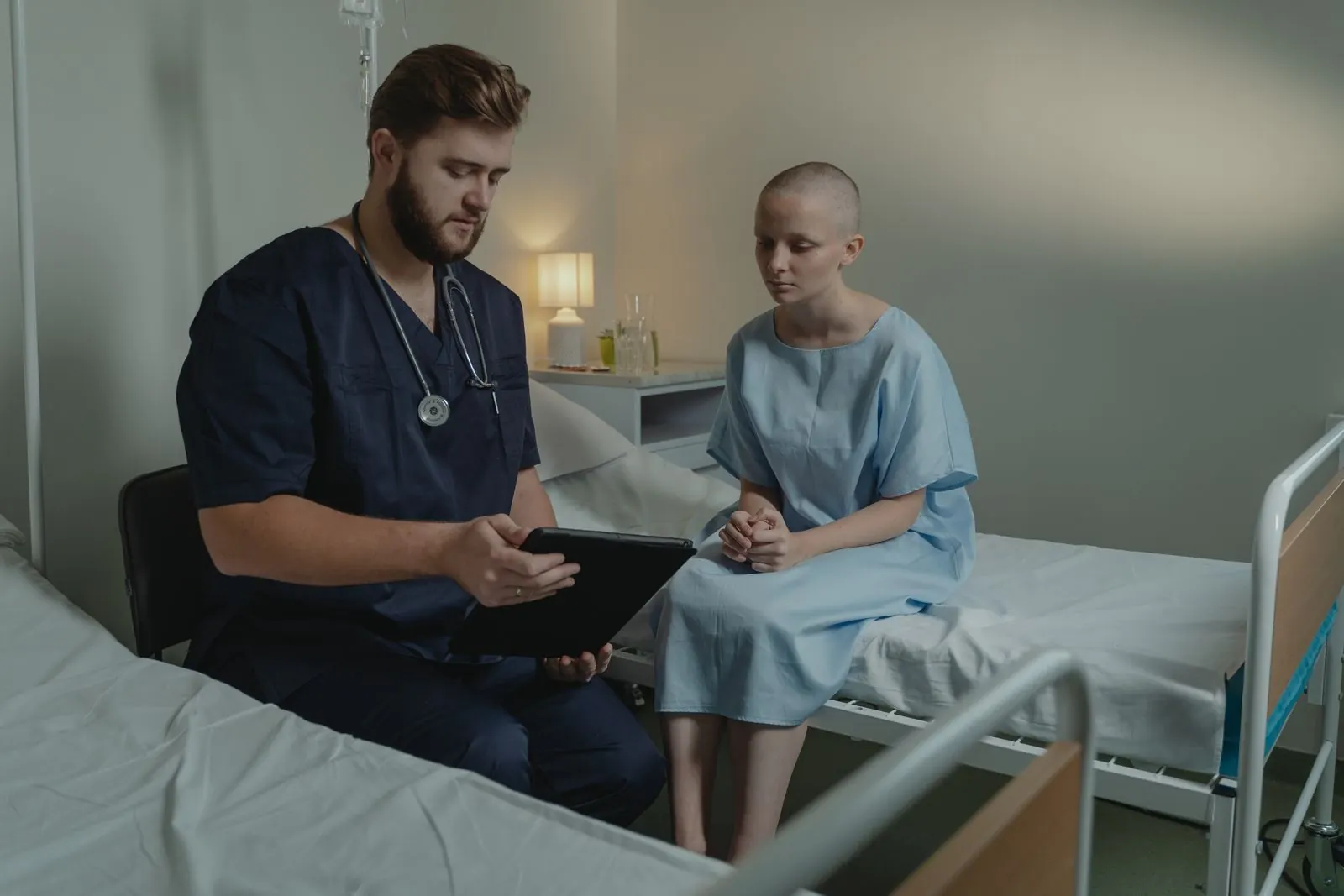 A doctor reviewing a tablet with a patient in a hospital room