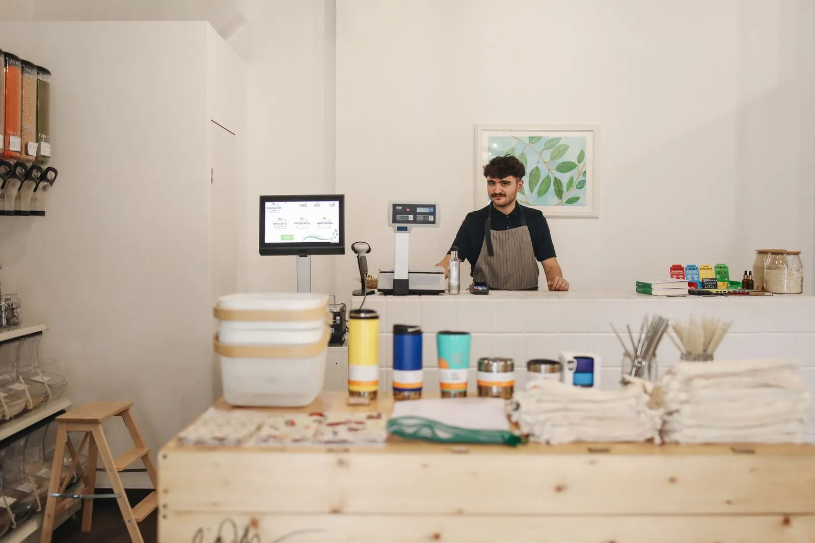 A shop owner behind a counter with a billing terminal