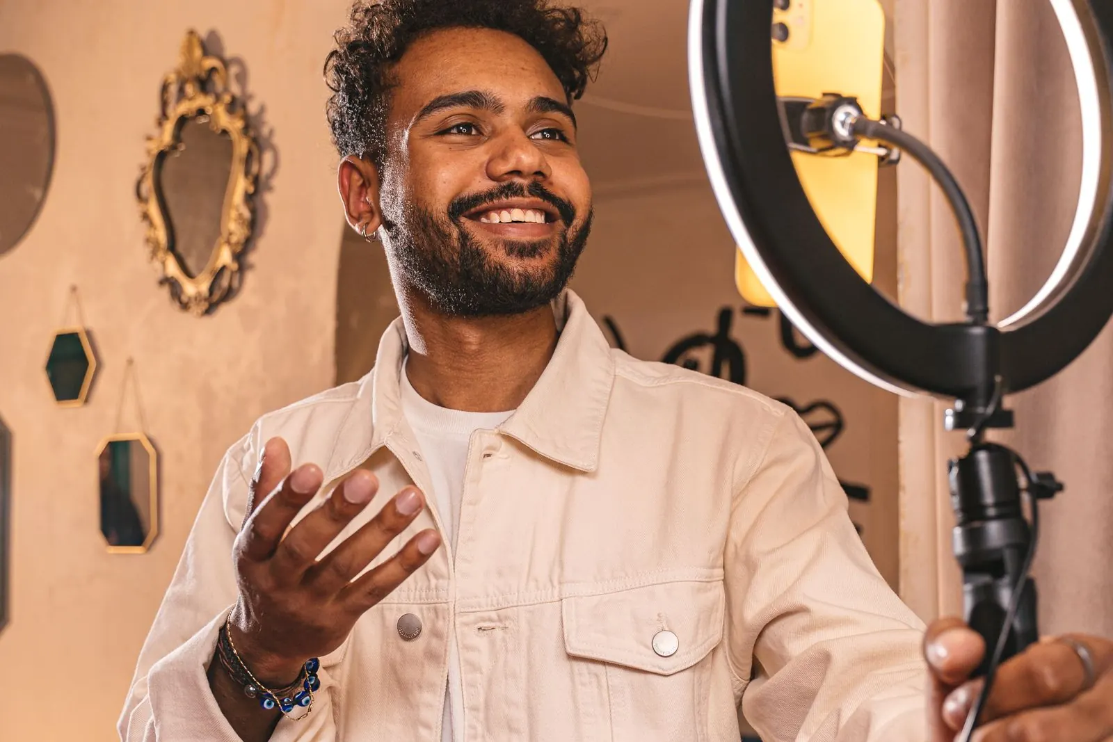 A smiling content creator speaking to a phone on a ring light stand