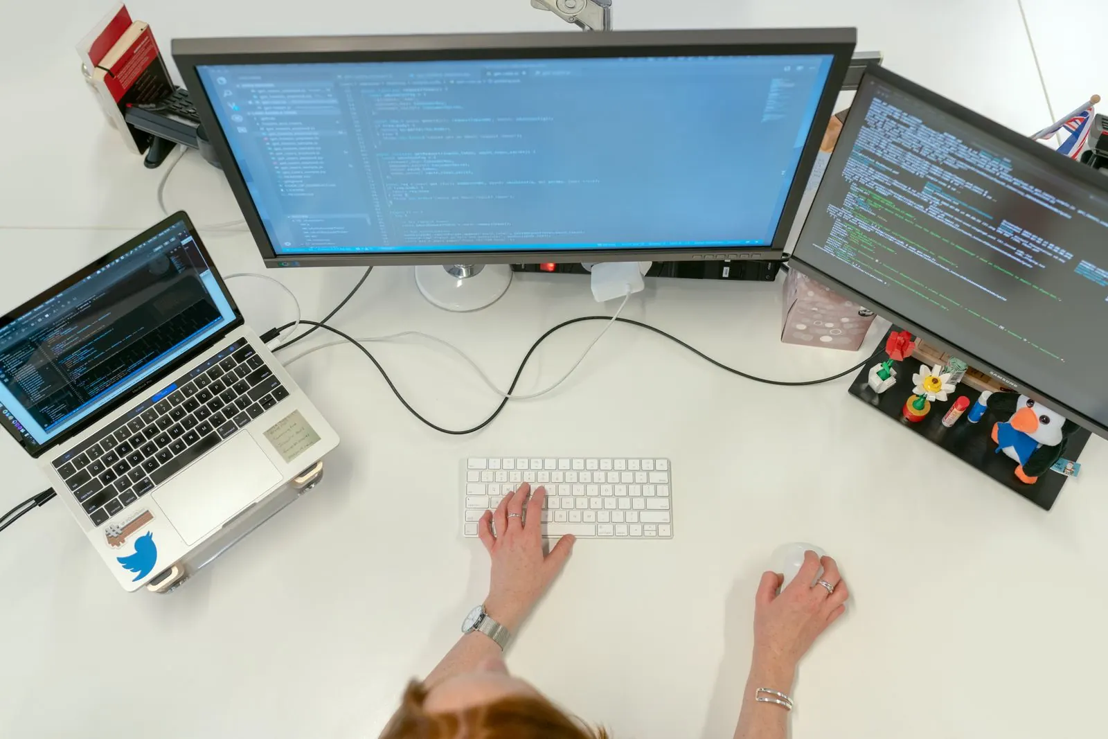 Overhead view of a developer working with code on a laptop and monitors